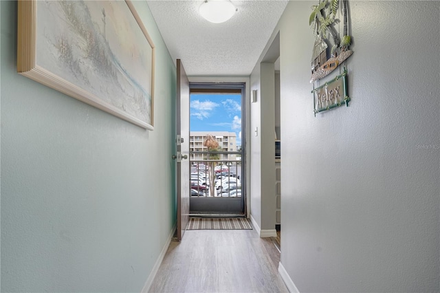 hallway featuring a wall of windows, a textured ceiling, and hardwood / wood-style floors