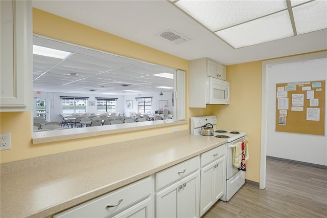 kitchen with light wood-type flooring, white cabinets, a paneled ceiling, and white appliances