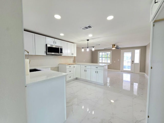 kitchen with white cabinetry, hanging light fixtures, kitchen peninsula, and ceiling fan