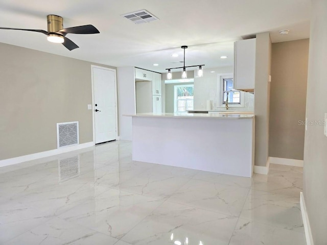 kitchen featuring ceiling fan, white cabinetry, decorative backsplash, and hanging light fixtures