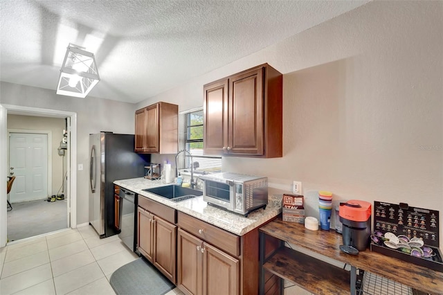 kitchen with dishwasher, sink, a textured ceiling, and light tile patterned floors