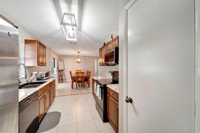 kitchen featuring sink, a textured ceiling, light tile patterned floors, pendant lighting, and black appliances