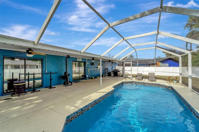 view of swimming pool with a patio, ceiling fan, and glass enclosure