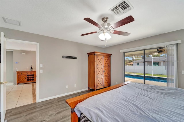 bedroom featuring access to exterior, baseboards, visible vents, and wood finished floors