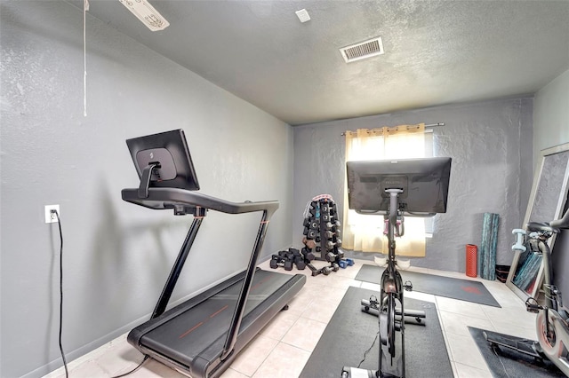 workout room featuring visible vents, a textured wall, a textured ceiling, and light tile patterned flooring