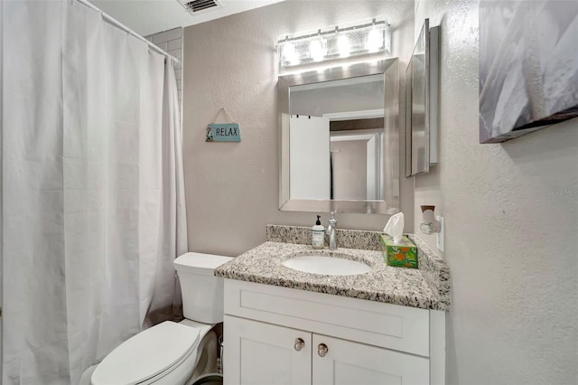 bathroom featuring visible vents, a textured wall, vanity, and toilet