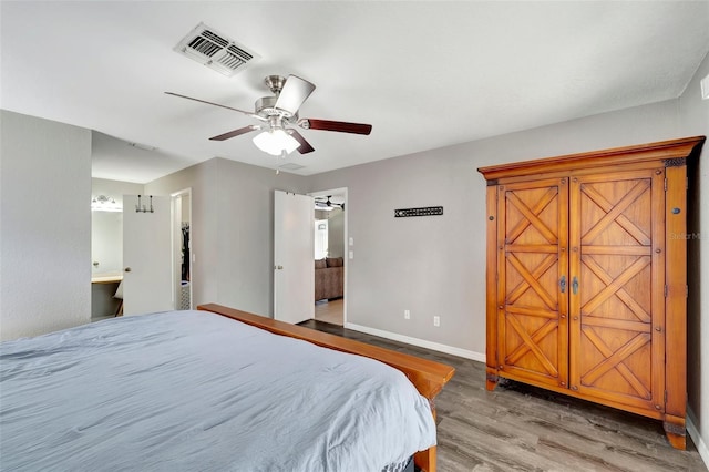 bedroom with visible vents, ensuite bathroom, a ceiling fan, wood finished floors, and baseboards