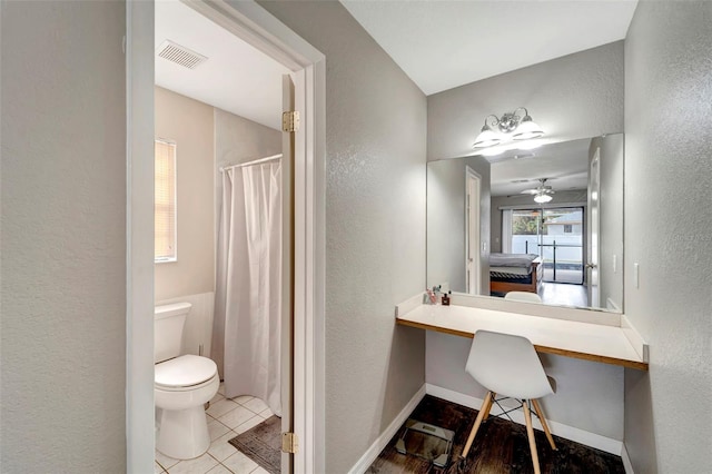 full bath featuring ensuite bathroom, a textured wall, toilet, visible vents, and baseboards