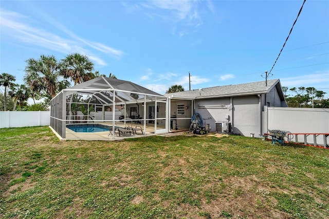 rear view of property featuring glass enclosure, a fenced backyard, a yard, a fenced in pool, and a patio area