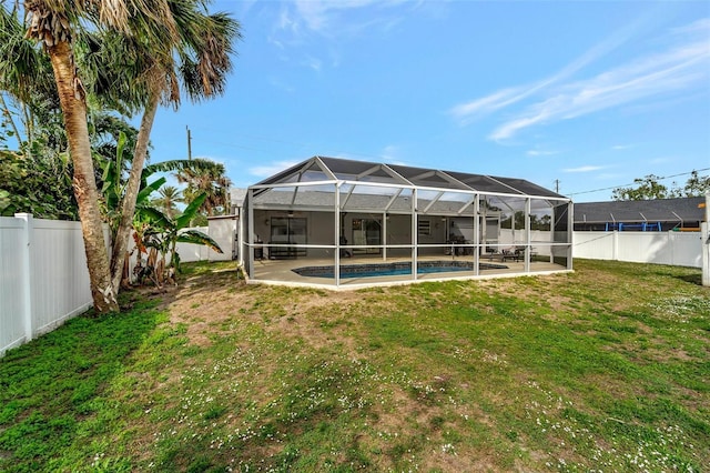 rear view of property featuring a lawn, a fenced backyard, a lanai, and a fenced in pool