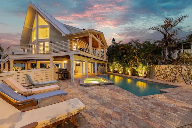 pool at dusk with a grill, a patio, and an in ground hot tub