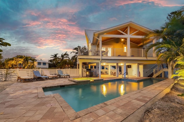 pool at dusk featuring a patio area and a jacuzzi