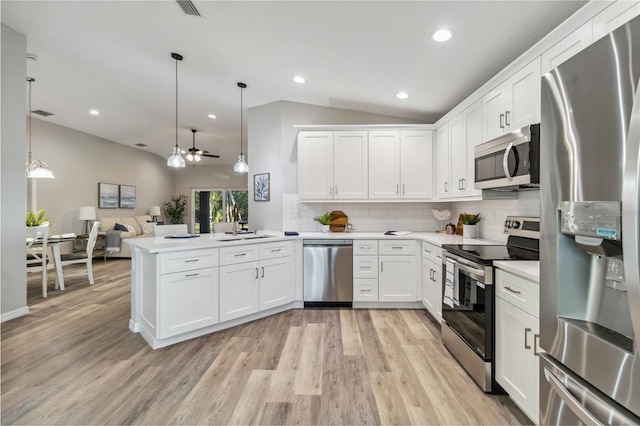 kitchen featuring hanging light fixtures, appliances with stainless steel finishes, kitchen peninsula, and vaulted ceiling