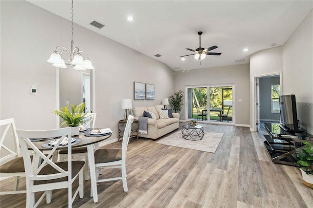 living room featuring ceiling fan with notable chandelier, vaulted ceiling, and light wood-type flooring