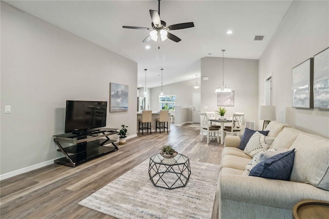 living room featuring ceiling fan with notable chandelier, wood-type flooring, and high vaulted ceiling