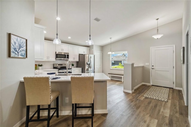 kitchen featuring sink, a breakfast bar area, appliances with stainless steel finishes, white cabinetry, and vaulted ceiling