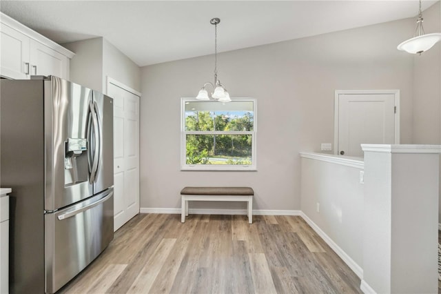 kitchen featuring white cabinetry, an inviting chandelier, decorative light fixtures, light hardwood / wood-style flooring, and stainless steel fridge