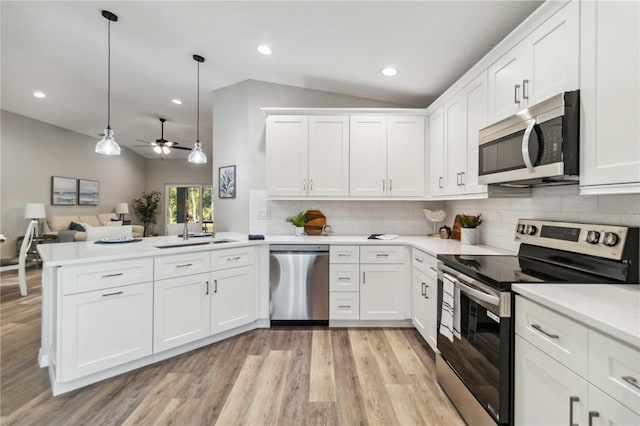 kitchen featuring lofted ceiling, white cabinetry, appliances with stainless steel finishes, kitchen peninsula, and pendant lighting