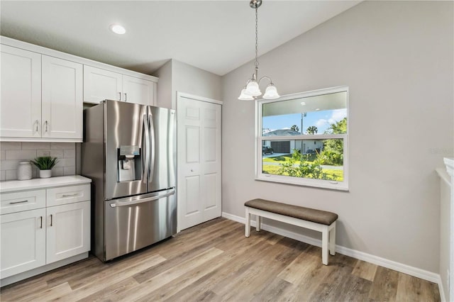 kitchen featuring decorative light fixtures, tasteful backsplash, white cabinets, a notable chandelier, and stainless steel fridge with ice dispenser