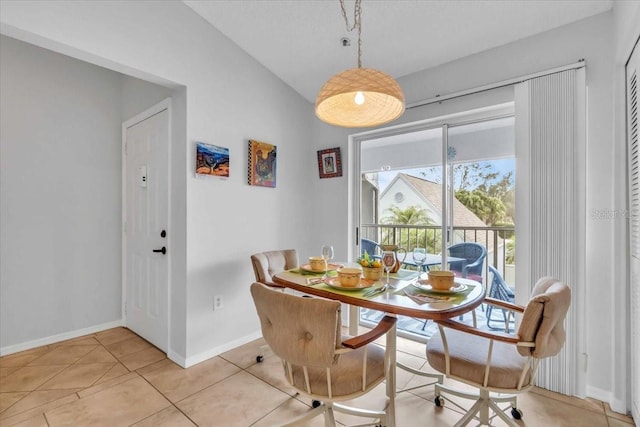 tiled dining space featuring vaulted ceiling