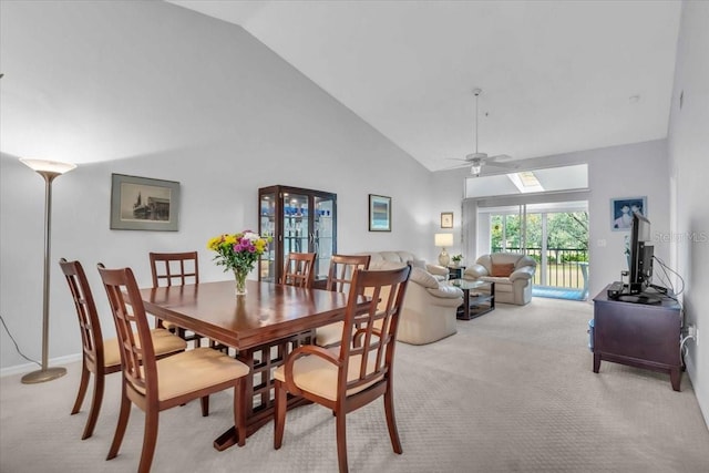 dining area with ceiling fan, light colored carpet, and high vaulted ceiling