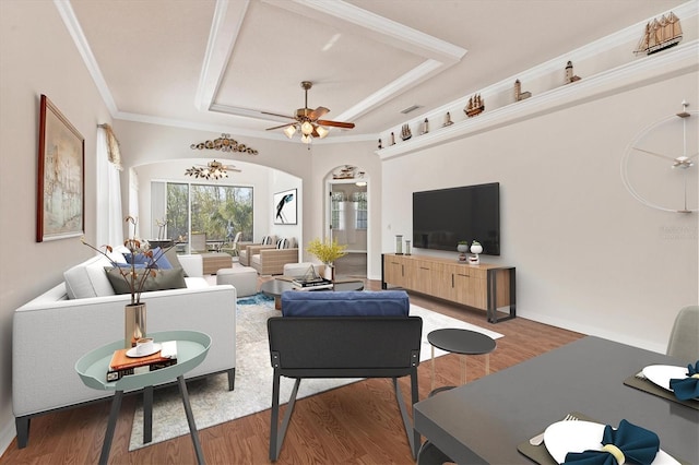 living room with hardwood / wood-style flooring, a tray ceiling, crown molding, and ceiling fan