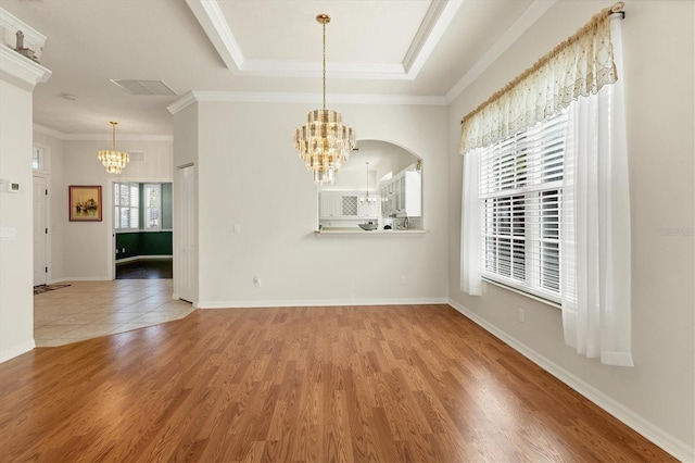 interior space featuring hardwood / wood-style floors, a tray ceiling, a notable chandelier, and a healthy amount of sunlight