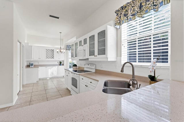 kitchen featuring hanging light fixtures, sink, white cabinets, light tile patterned floors, and white appliances