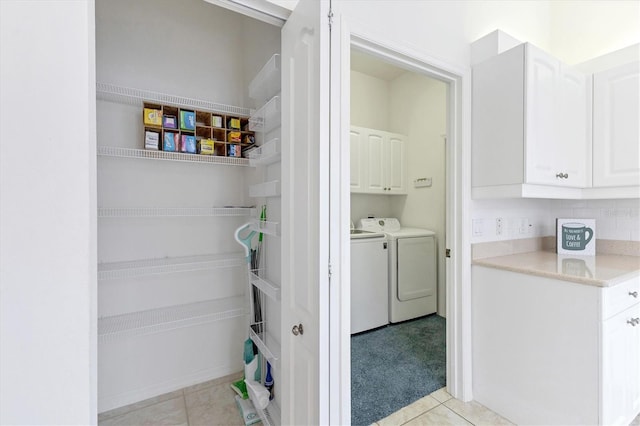 laundry area featuring washing machine and clothes dryer, light tile patterned floors, and cabinets