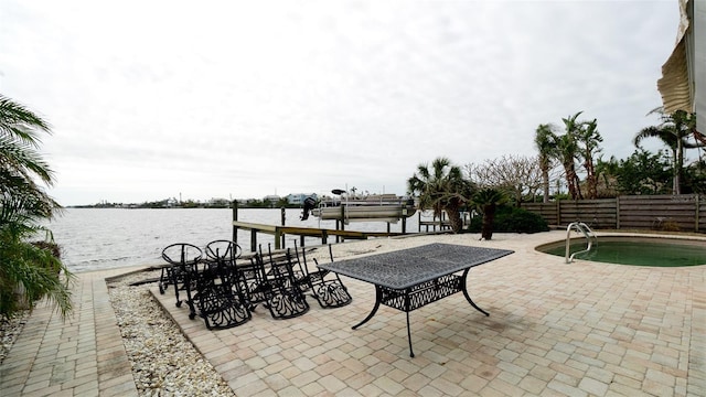 view of patio featuring a fenced in pool, a water view, and a boat dock