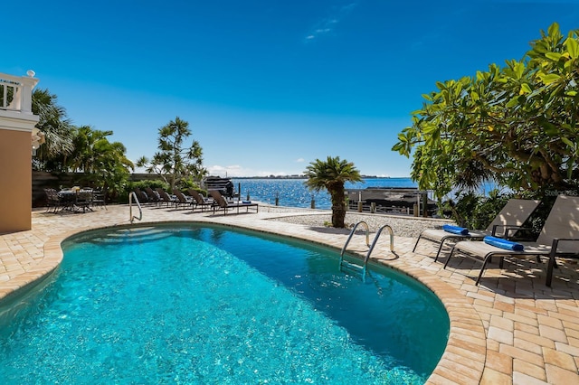 view of swimming pool with a patio area and a water view