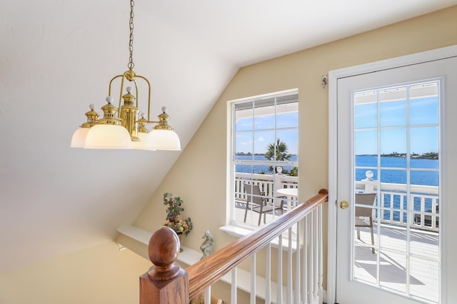 stairs with vaulted ceiling, a chandelier, and a water view