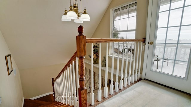 staircase featuring vaulted ceiling and an inviting chandelier