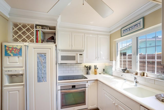 kitchen featuring wall oven, black electric stovetop, decorative backsplash, ornamental molding, and white cabinets