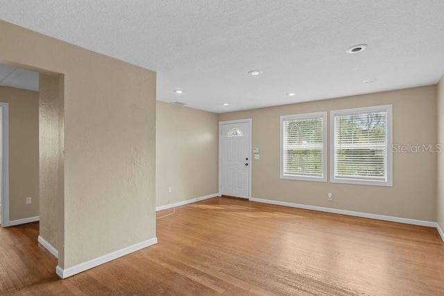 interior space featuring light wood-type flooring and a textured ceiling