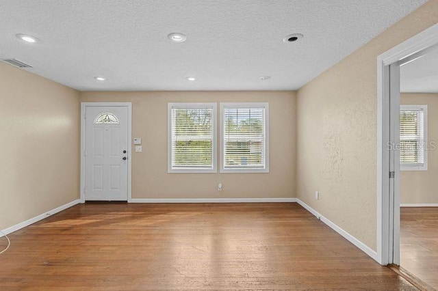 foyer entrance with wood-type flooring and a textured ceiling