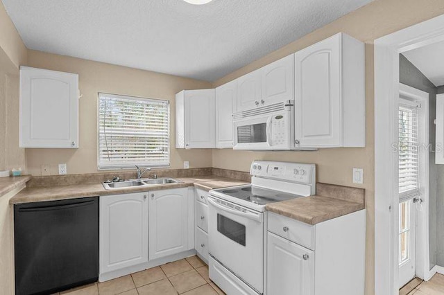 kitchen featuring sink, white cabinets, plenty of natural light, light tile patterned floors, and white appliances