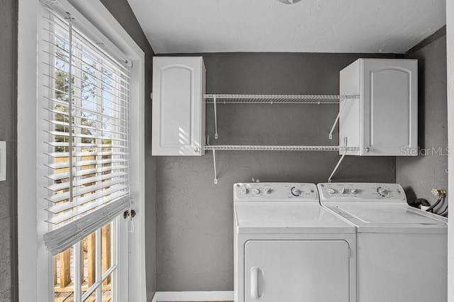 clothes washing area with cabinets and washing machine and clothes dryer