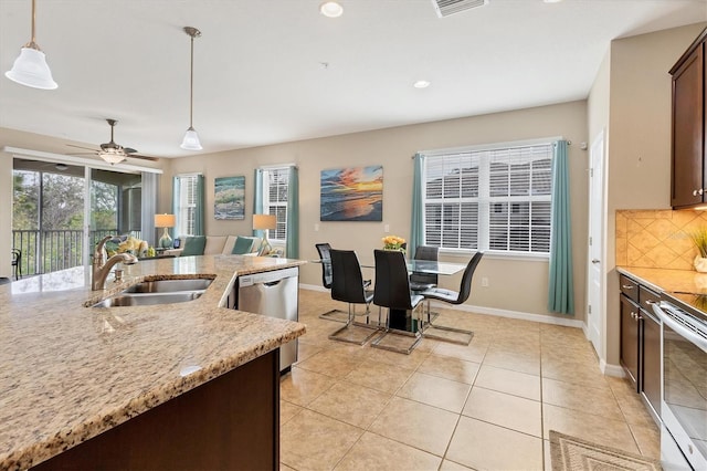 kitchen featuring appliances with stainless steel finishes, pendant lighting, tasteful backsplash, light stone countertops, and dark brown cabinets