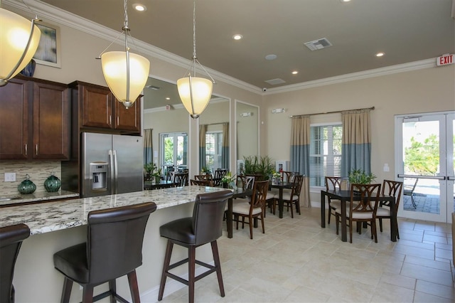 kitchen with a kitchen breakfast bar, decorative backsplash, stainless steel refrigerator with ice dispenser, light stone countertops, and french doors