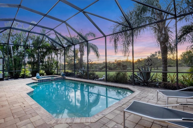 pool at dusk with a patio area, a lanai, and an in ground hot tub