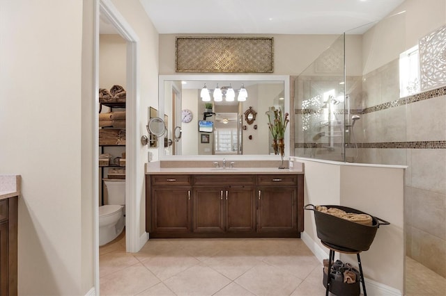 bathroom with tiled shower, toilet, tile patterned flooring, and vanity