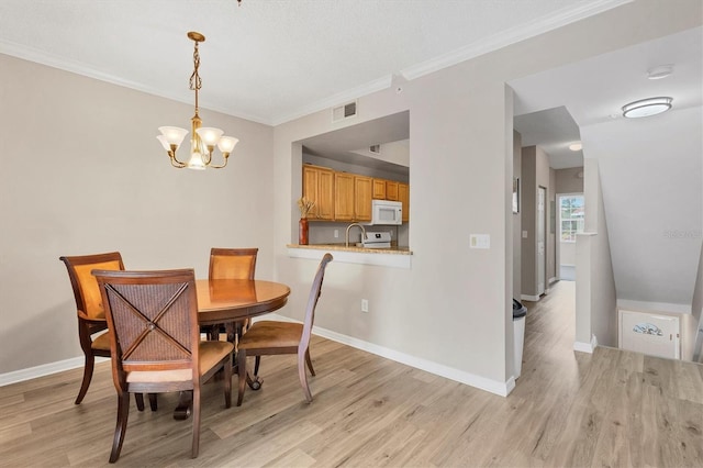 dining area with light wood-type flooring, an inviting chandelier, sink, and crown molding