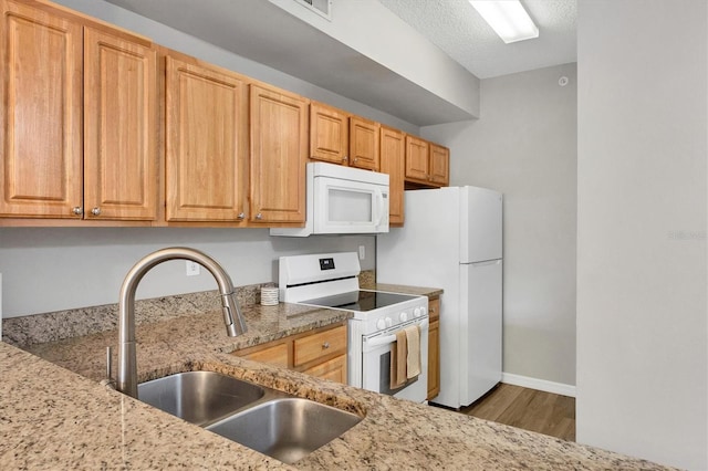 kitchen with hardwood / wood-style flooring, white appliances, light stone countertops, a textured ceiling, and sink