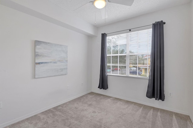 spare room with ceiling fan, a textured ceiling, and light carpet