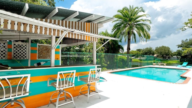 view of pool featuring a bar, a pergola, and a patio