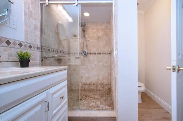 bathroom with toilet, a shower with door, tile patterned floors, crown molding, and vanity