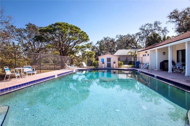 view of swimming pool with an outbuilding, a patio, and grilling area