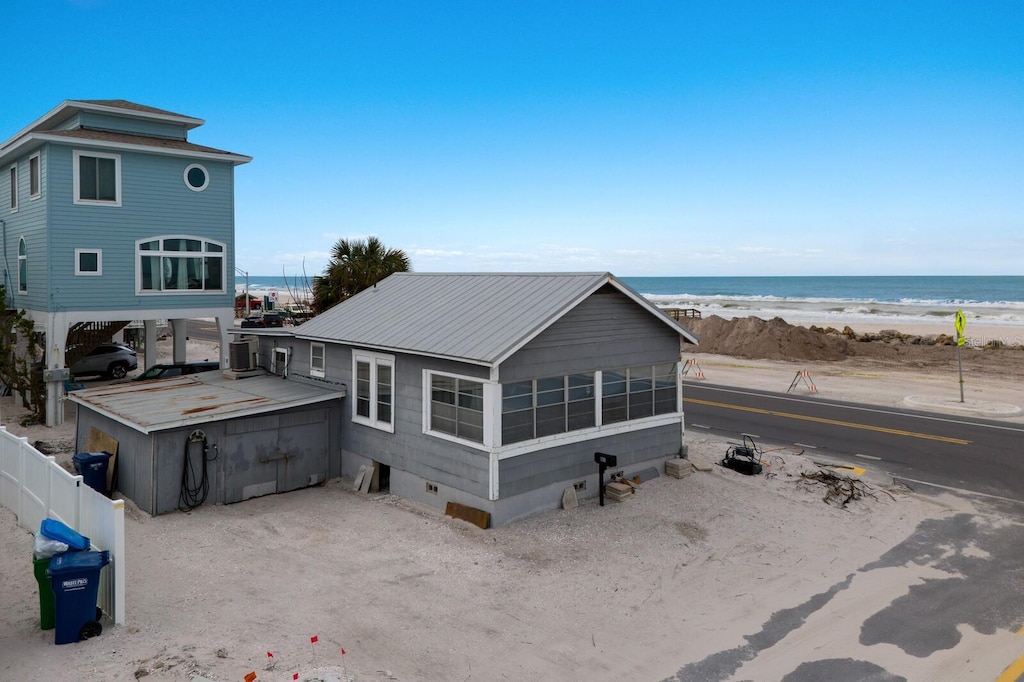 rear view of house with a water view, a beach view, and a sunroom