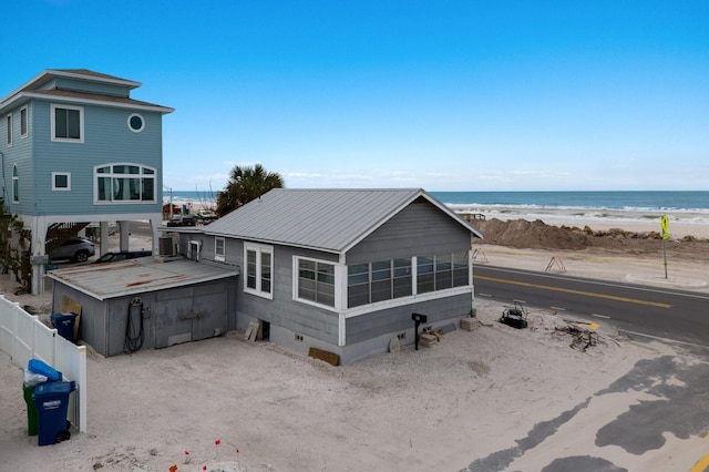 rear view of house with a water view, a beach view, and a sunroom